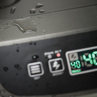 The image shows a close up of a Desert Plunge cold plunge chiller unit. The display on the chiller is showing with the digital numbers "40" showing in green. The other buttons on the chiller are out of focus and there is some water from the cold plunge tub splashed on the cold plunge chiller. You can also see a small red light above one of the buttons.