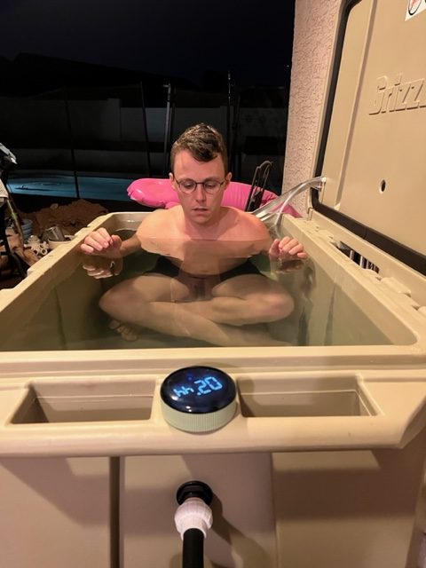A photo of a man meditating during cold therapy in his tan cold plunge tub from Desert Plunge.