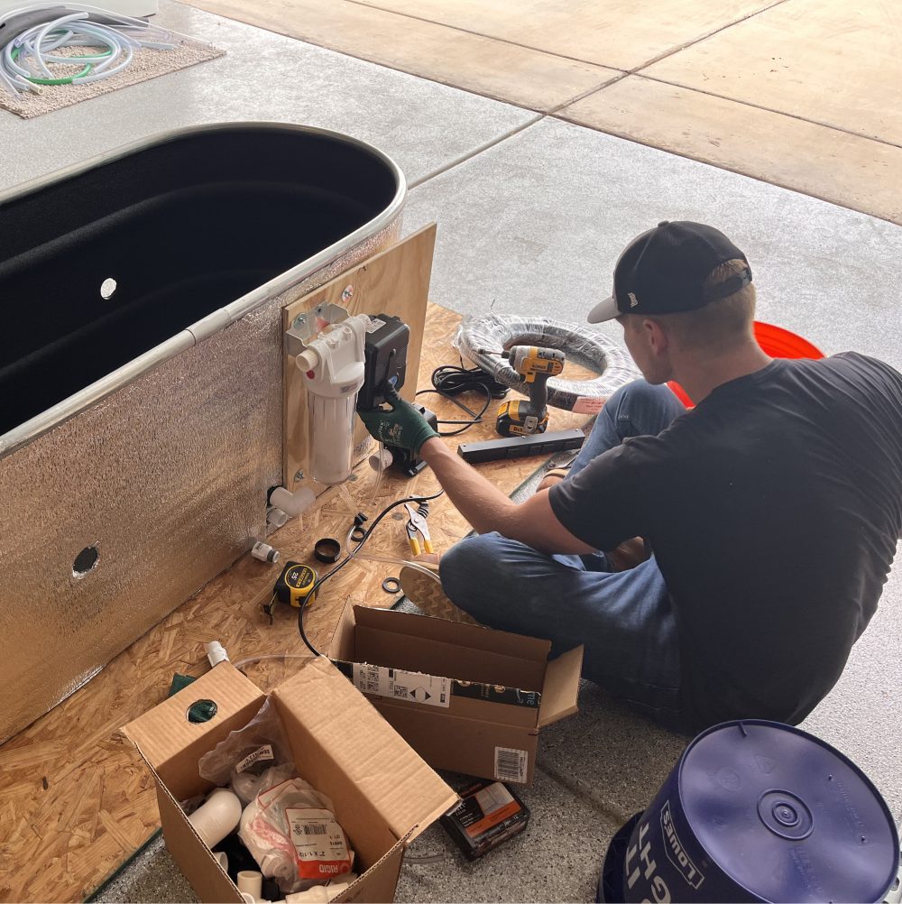 A photo of Matt working with cold plunge components to add to a Desert Plunge cold therapy tub.
