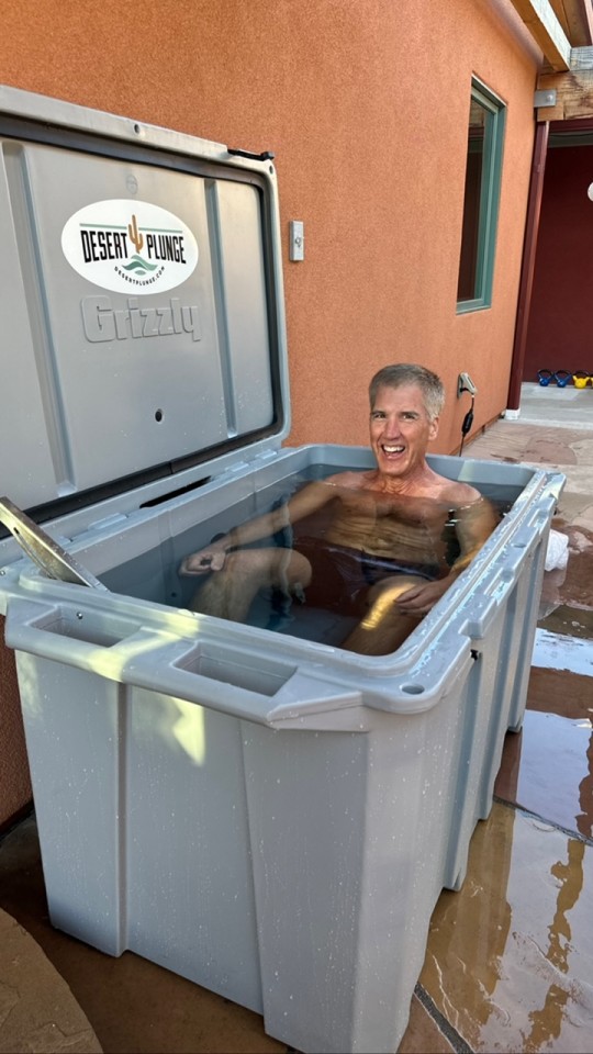 A man enjoying his cold plunge tub outside.